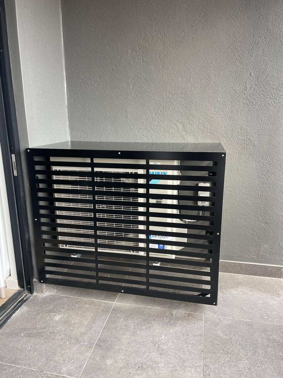 Black air conditioner cover for outdoor unit, designed for airflow and protection against weather elements.
