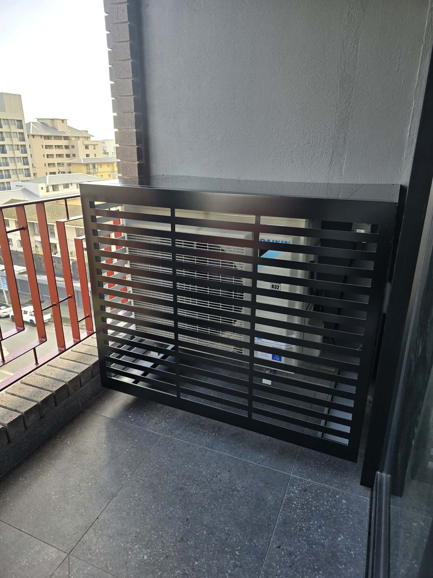 Modern black air conditioner cover on a balcony, designed for weather protection and airflow.